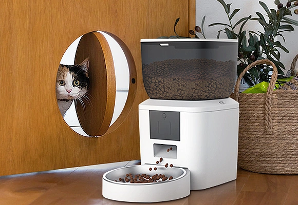Top Rated Smart Pet Product Manufacturers in China Petrusts Automatic Cat Feeders of Smart Pet Product Manufacturers in China A tricolor cat peeking through a cat door next to a white automatic cat feeder, showing a product from a directory of smart pet product manufacturers in China.