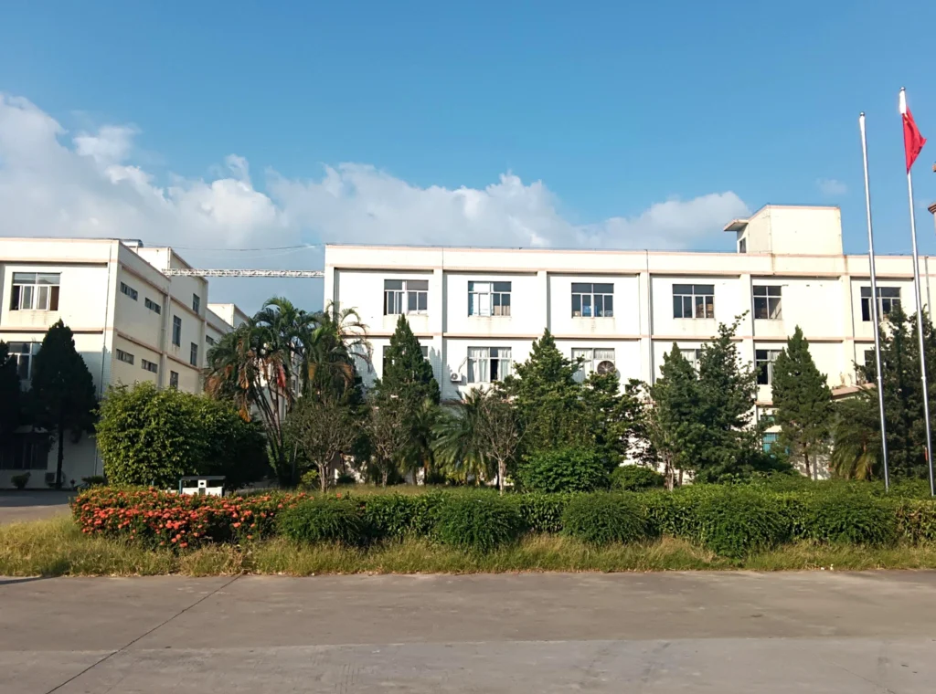 Exterior view of the Petrust® Contact page manufacturing facility in Anyi Industrial Park, Huizhou, showing a white factory building surrounded by green landscaping.
