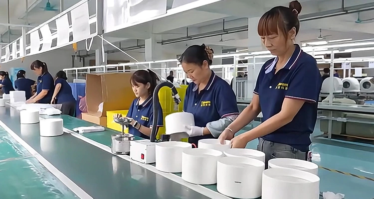 Factory workers on a clean assembly line assembling white plastic components for pet devices, demonstrating the manufacturing capacity being highlighted at MEGAZOO 2025 Korea.