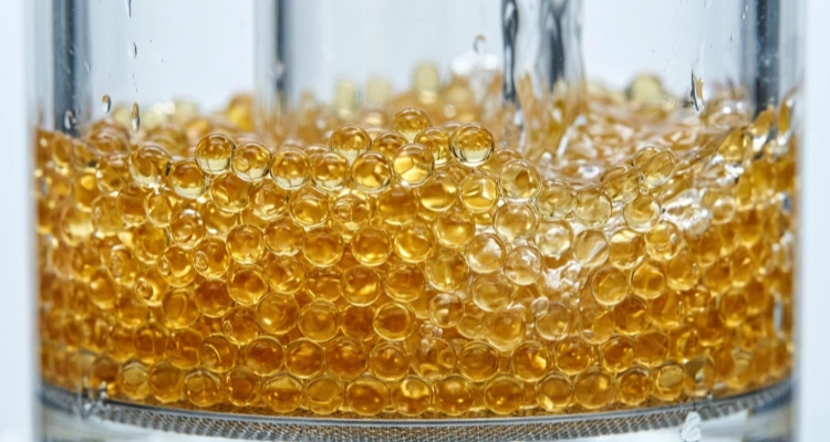 Macro shot of golden ion-exchange resin beads inside pet water fountain filters that soften tap water by removing magnesium and calcium.